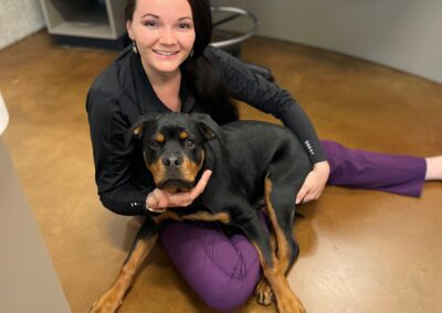 Smiling woman pets Rottweiler dog.
